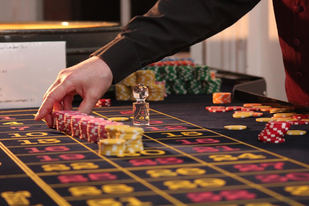 Live casino dealer table with cards and roulette wheel in a studio setting